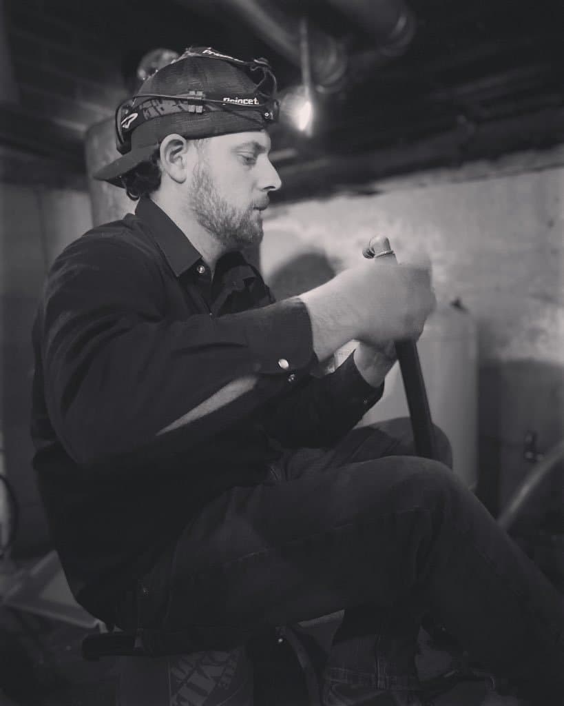 Plumber working in a tight crawlspace by headlamp